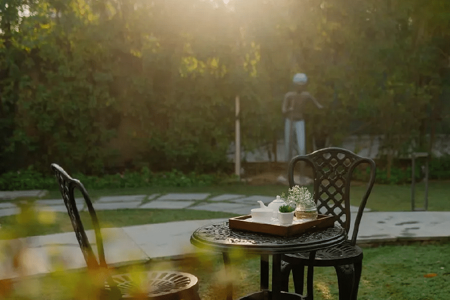 Outdoor seating with two chairs and a table on grass at Karma Chalets during sunset.