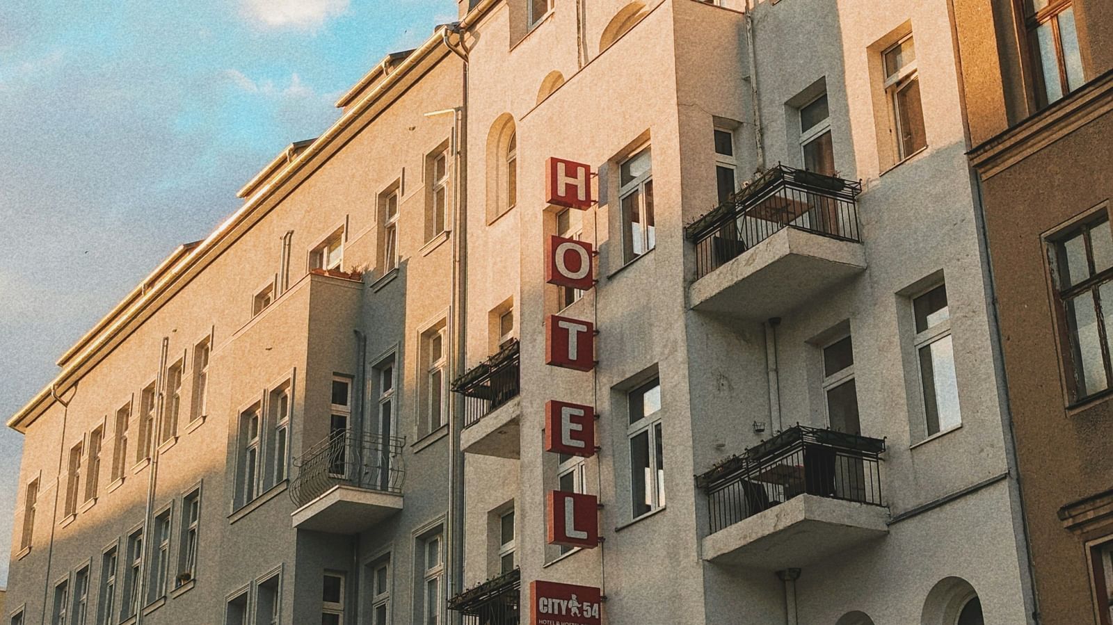  A low-angle view of a row of European-style buildings with balconies under a blue sky