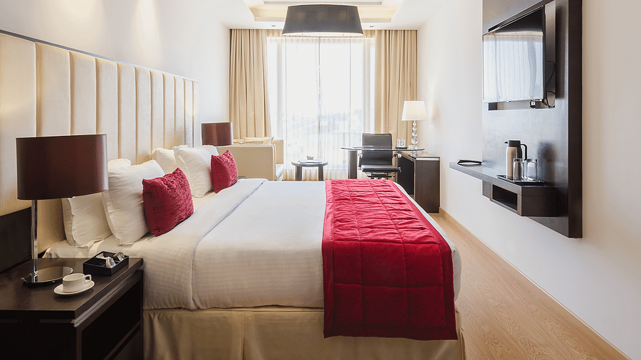 A spacious hotel room with a king size bed with a white duvet and red throw blanket - TGI Grand Fortuna, Hosur