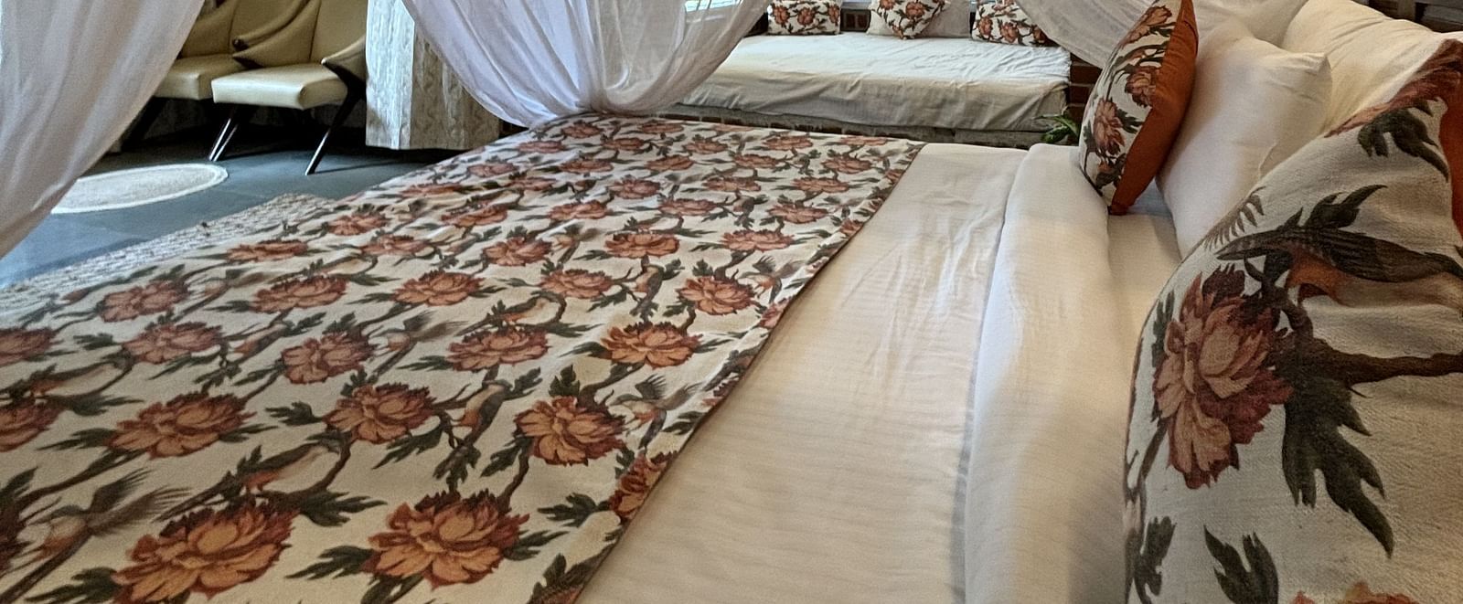 Four-poster canopy bed with floral bedding in a warmly lit room at Tisya Farms, Gurgaon