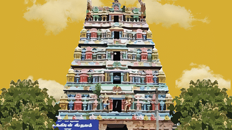 Colourful gopuram of a temple framed by lush greenery and a golden sky.