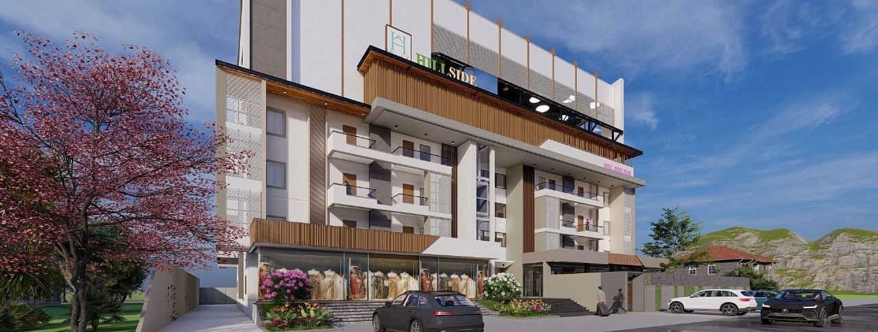 A facade image of the hotel building with a tree with blossoms near it, and cars parked in front - Livancia Hillside, Mysore