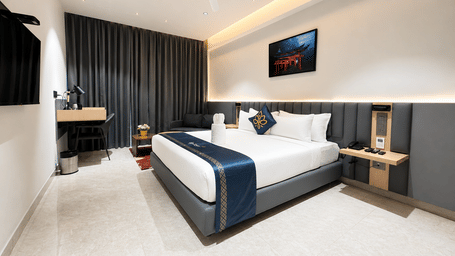Premium Suite with a king size bed and wall mounted television at Hotel Kyzen, Shamshabad Airport, Hyderabad.