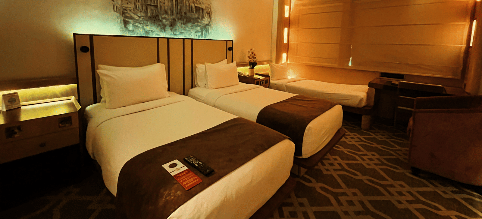 Two twin beds and a seating area and a single bed at the side of the room at Marco Polo Hotel.