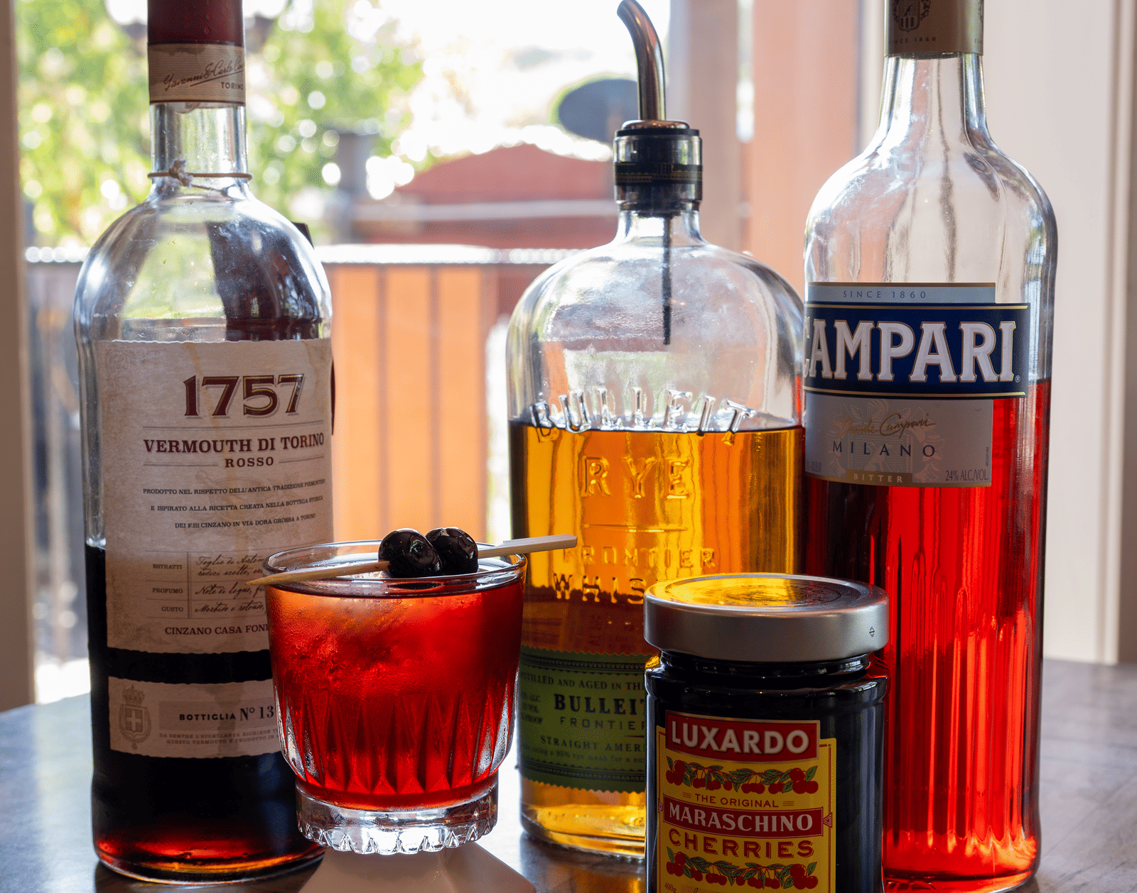 Assortment of spirits and ingredients for classic cocktails displayed by a window at The Groveland Hotel.