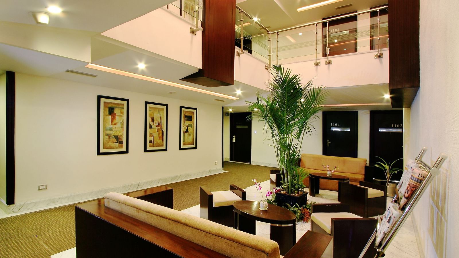 A modern and spacious hotel lobby with a two-story ceiling, framed artwork on the walls, and comfortable seating areas - The President Hotel Jayanagar, Bangalore