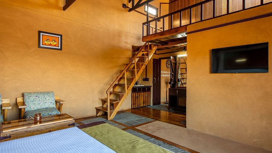 Cosy loft-style bedroom with stone and wooden finishes, featuring a staircase leading to the upper loft area.