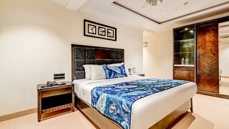 Deluxe room with a private balcony featuring a large bed, flanked by wooden bedside tables, and a photo frame mounted above the headboard