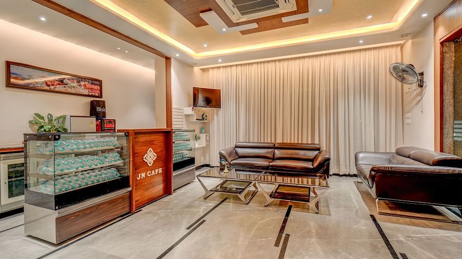 The reception area at Harigovinda's JNStay, with a desk to the side and a cushioned sofa with a table in front