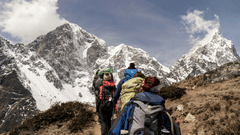A group of people on a trek surrounded by snow capped mountains