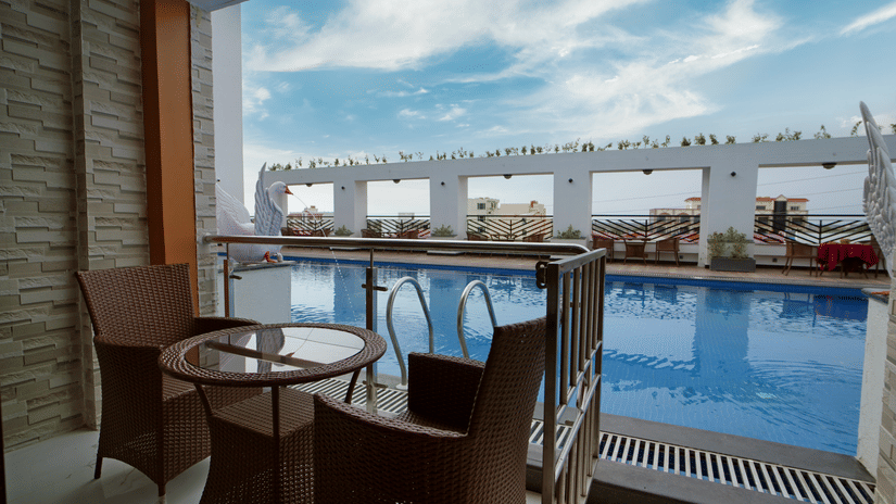 A view of chairs and tables arranged beside swimming pool with a small table with views of the swimming pool at Shanti Seaview Resort & Spa