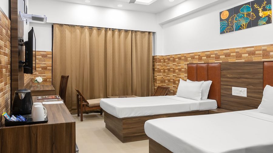 A hotel room with two single beds, a TV stand with a wall mount TV, a wall painting, a desk, and closed curtains.- Clarks Inn Express, Near Jammu Bari Brahmana Railway Station