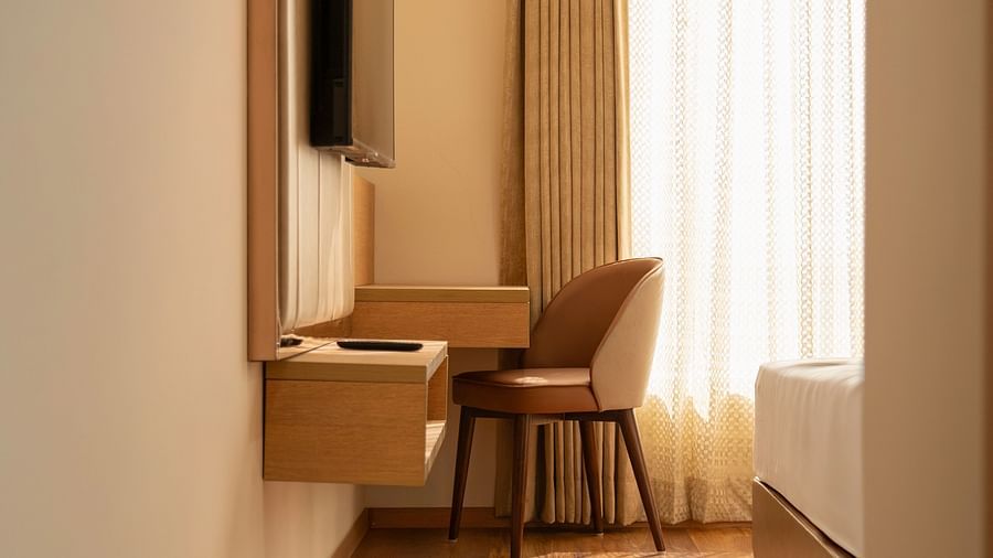 A hotel room with a desk and chair, a flat-screen TV, and a large window with curtains - Clarks Inn, Indore