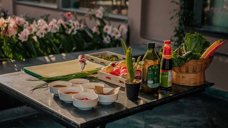 Sushi platter and fresh vegetables arranged on a dark table outdoors. Flowers and a building are visible in the blurred background - Clarks Safari, Pushkar