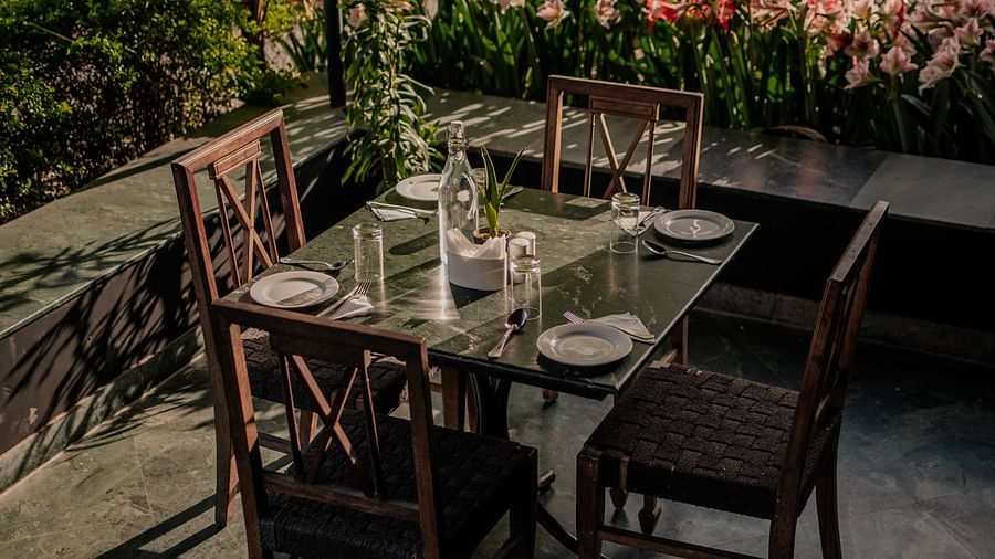 Outdoor dining arrangement for four with a view of greenery and beautiful blossoms. The table is set with plates and cutlery - Clarks Safari, Pushkar