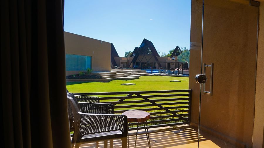 balcony with a chair and table with a view of lush green garden at Jagira Ananta Elite