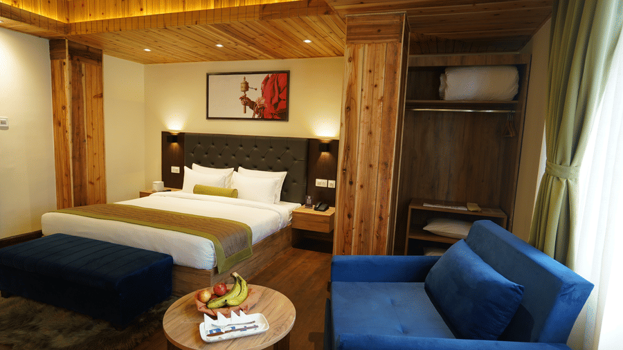 Bedroom with a bed, sofa seating, and wooden furnishings.