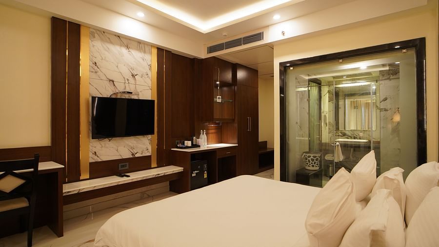 a double bed with many pillows on it and a tv wall mounted opposite the bed inside one of the rooms - Shanti Seaview Resort & Spa