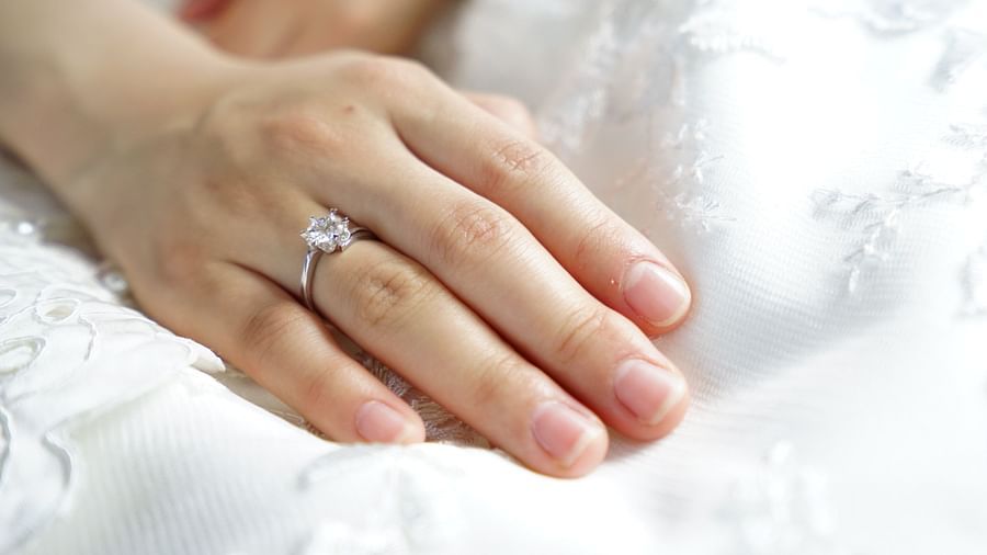 Hand with diamond ring resting on white dress
