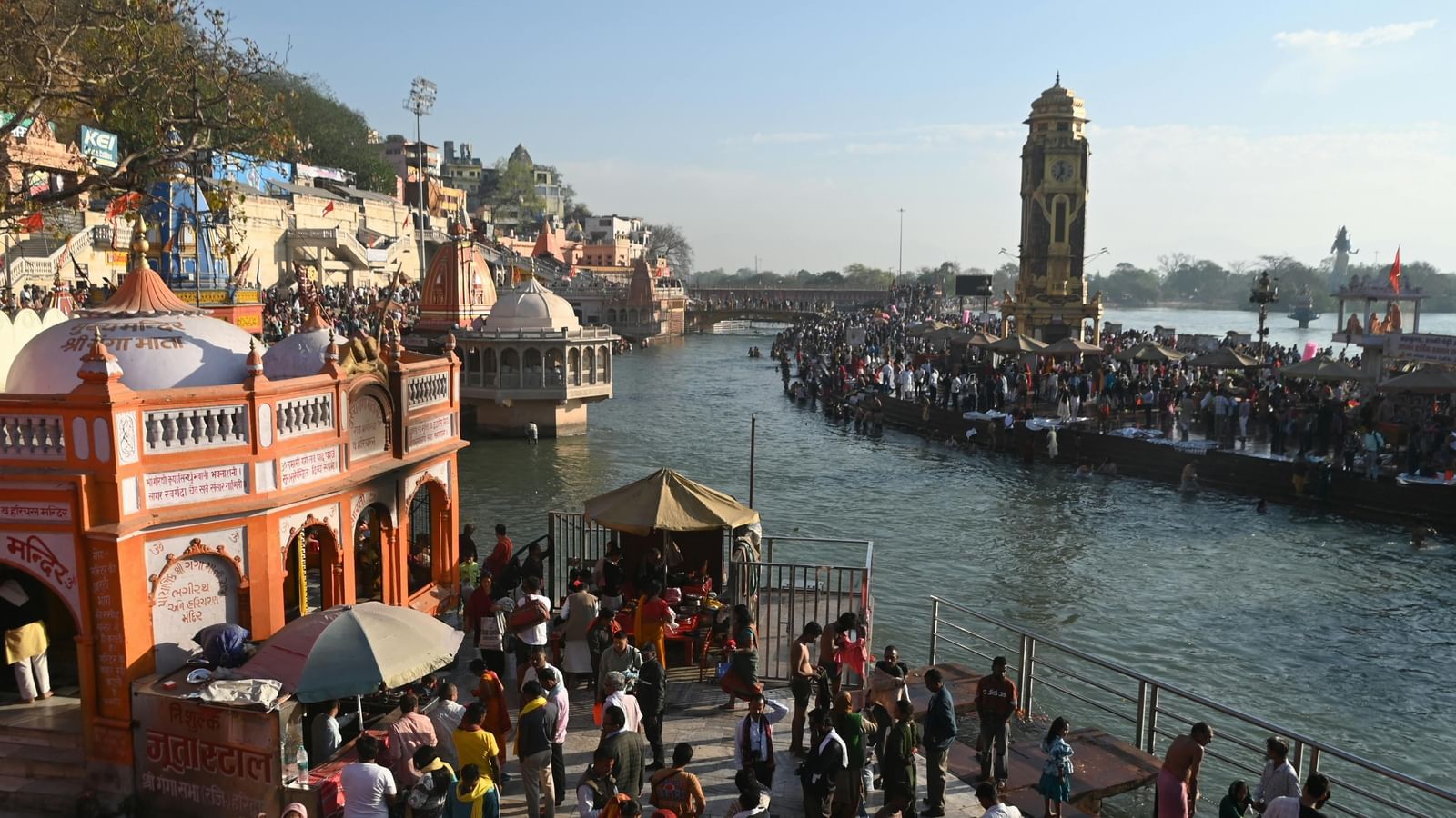 Pilgrims at Har Ki Pauri, Haridwar, participating in a spiritual ritual along the Ganges River near historic temples.