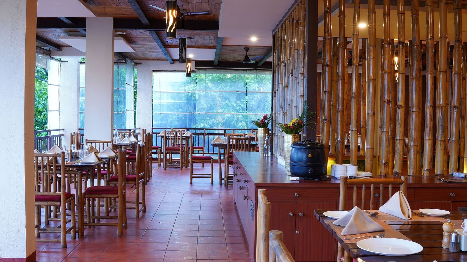 The dining area at Forest Escapes Koyna features tables and chairs, with natural light streaming in.