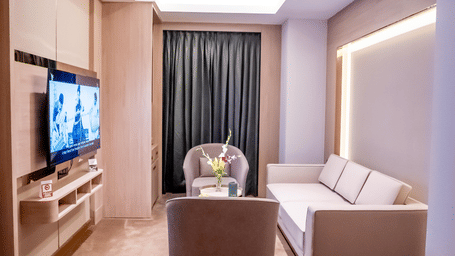 Living area with seating, TV and a window with a curtain in the background at ASTER GRAND BY ZENQ SAKET.