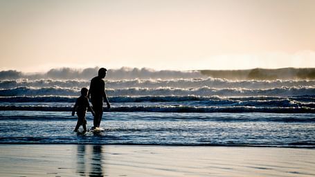Two people strolling along the shore with ocean waves in the background