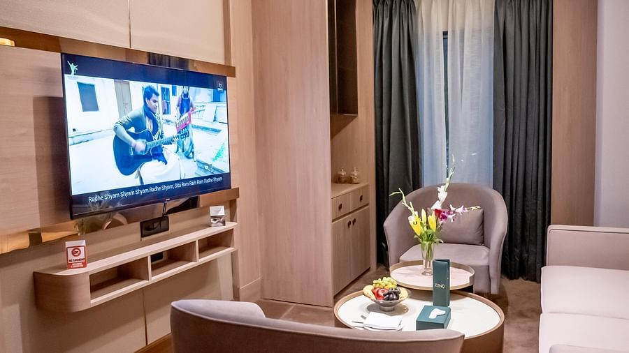 Living room set up with sofa, chairs, wall mounted TV and window with a curtain in the background at ASTER GRAND BY ZENQ SAKET.