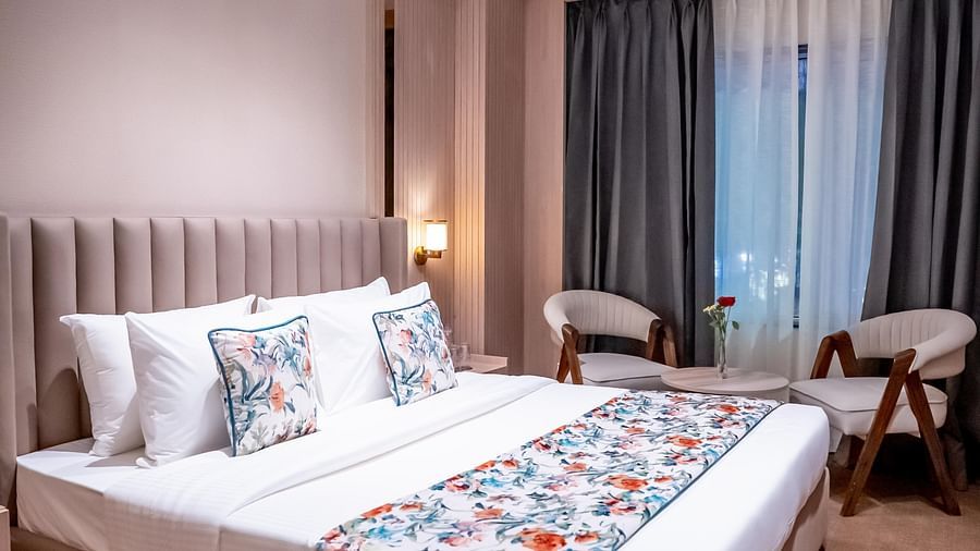 Bedroom with a queen size bed with chairs and window with a curtain in the background at ASTER GRAND BY ZENQ SAKET.