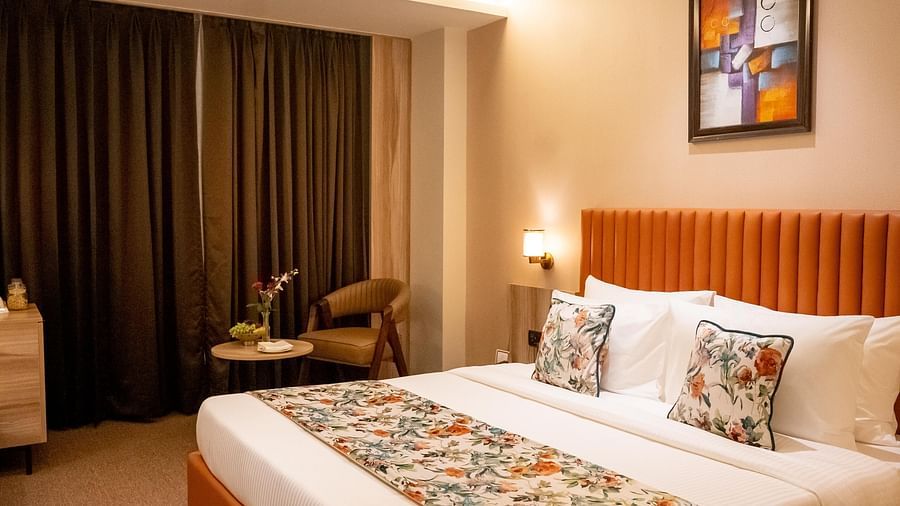 Superior Room at ASTER GRAND BY ZENQ SAKET with a bed, bed side table, a chair and a window with curtain in the background.