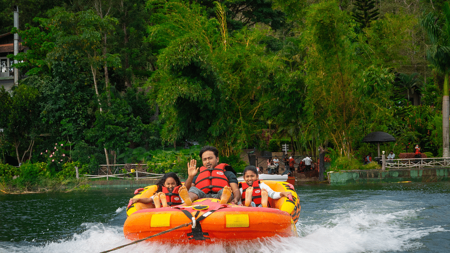Image of a man and two girls on a boat with trees in the background.