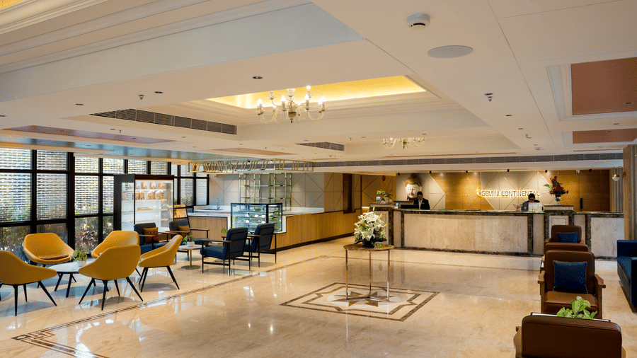 Lobby area of Gemini Continental featuring a decorative ceiling, multiple sofas and chairs, and a reception desk with hotel staff.