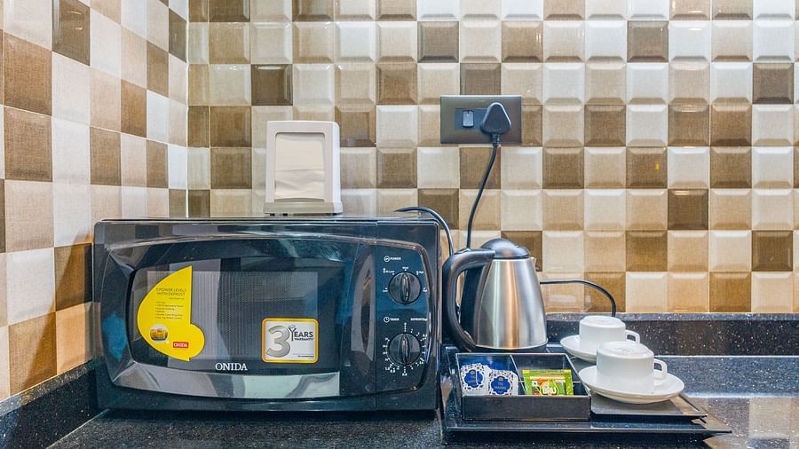 Image of a microwave and an electric kettle with cups on the side at Hotel Altitude, Madikeri.