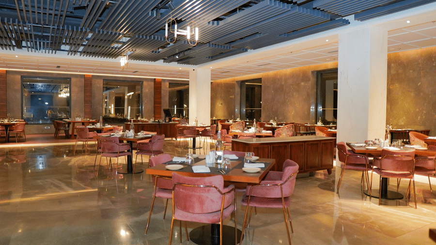 Interior view of the resort restaurant with modern decor, marble floors, and pink seating at Pushkara Resort & Spa.