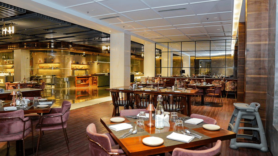 A bright, spacious fine dining restaurant with plush purple chairs and a high chair at Pushkara Resort & Spa.