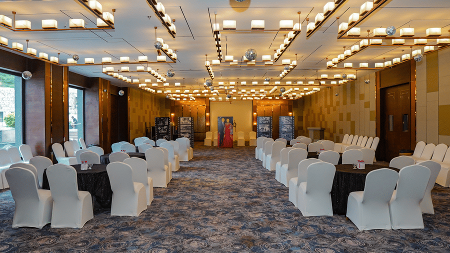 A view of a long event hall set up with multiple rows of chairs for an audience, showing the full length of the room.