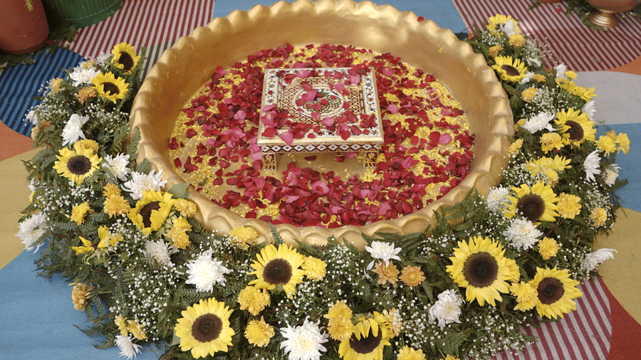 Traditional floral decor at Ramada Encore by Wyndham Chandigarh Zirakpur with a golden bowl filled with rose petals, a decorative stool at the center, and sunflowers and white flowers arranged around it.