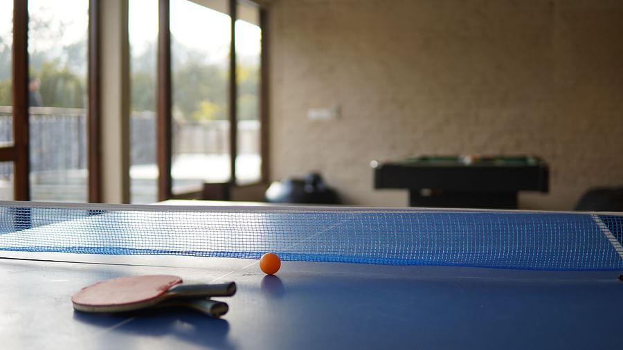 An indoor table tennis set up at Saraca Resort & Spa Corbett with large windows letting in light