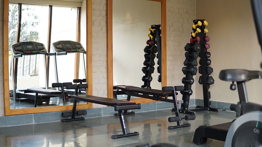 The gym at Saraca Resort & Spa Corbett with a dumbbell rack and benches