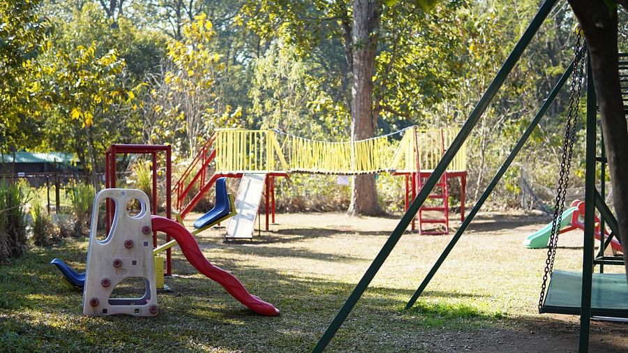 Kids Play Area at Saraca Resort & Spa Corbett with swings and a slide amidst trees