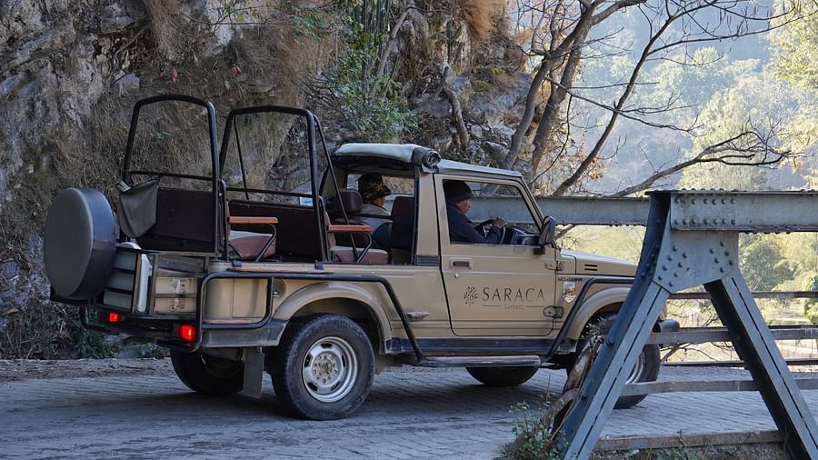 A jeep with an open back just about to pass through a suspended bridge during the day