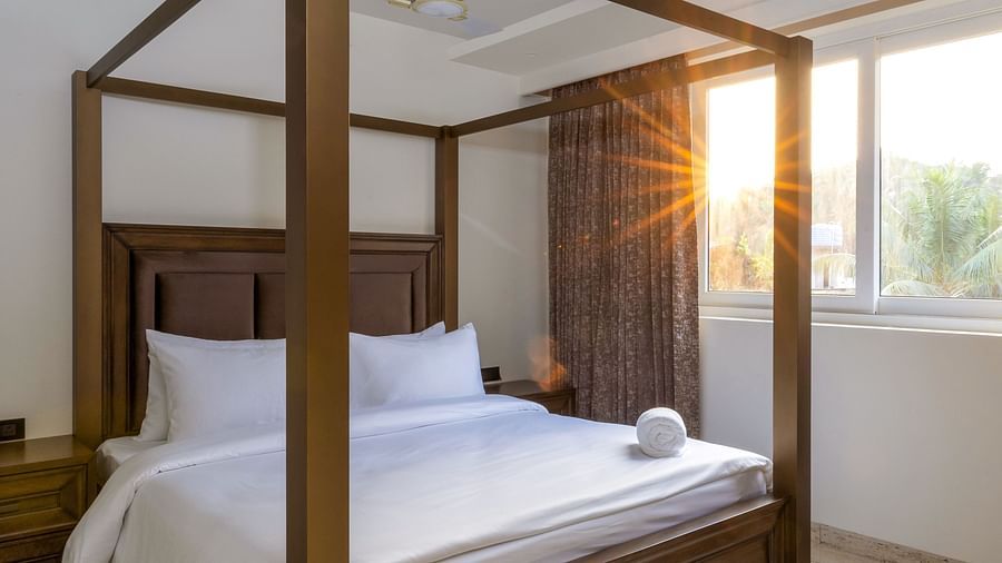 A double bed with wooden beams inside one of the rooms - The Tanisi Hotels & Resorts, Goa