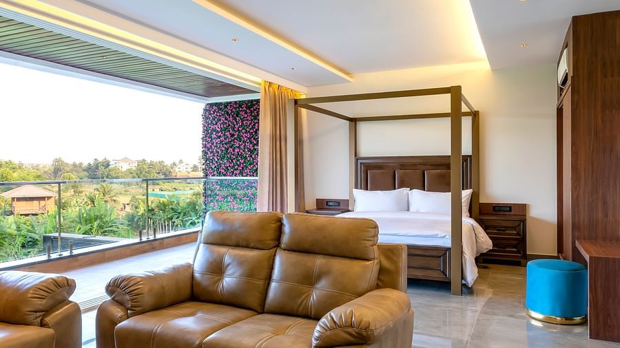 A double bed with wooden beams with a sofa in front of it inside one of the rooms - The Tanisi Hotels & Resorts, Goa