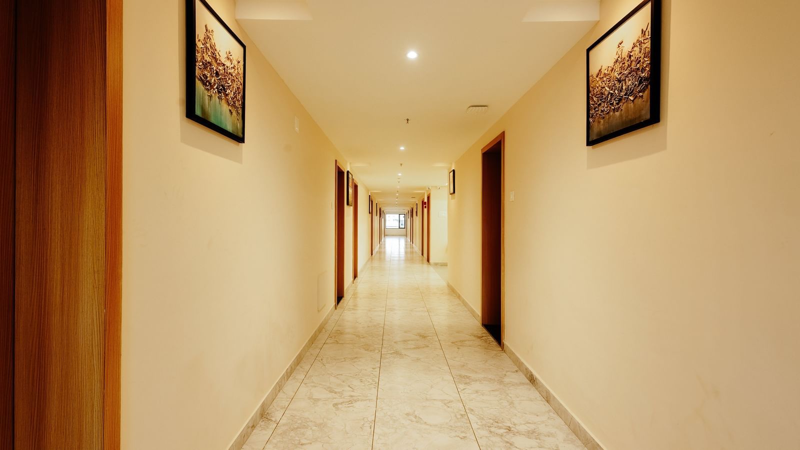 A neat and clean well-lit corridor at Daksh The Grand Gowardhan, Dwarka, leading to various guest rooms.