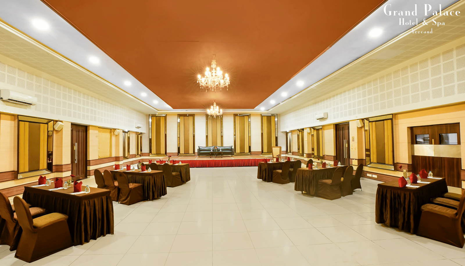 Large event space at Grand Palace, Yercaud arranged with sofa seating, open area, chandeliers, panoramic windows, and polished flooring for gatherings