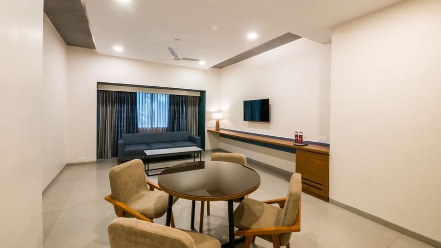 A spacious hotel living area with a round dining table and chairs, perfect for meals or work at Shilton Dee Cee.