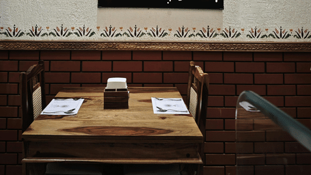 Close-up of a framed artwork hanging above a wooden dining area.