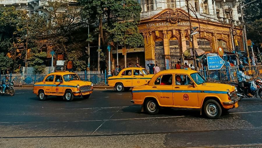 An image of the streets of Kolkata with yellow taxis and a building in the background