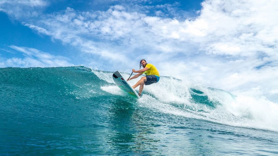 A surfer riding a powerful ocean wave, leaning forward on the surfboard while maintaining balance against the rushing water | Abaco Inn