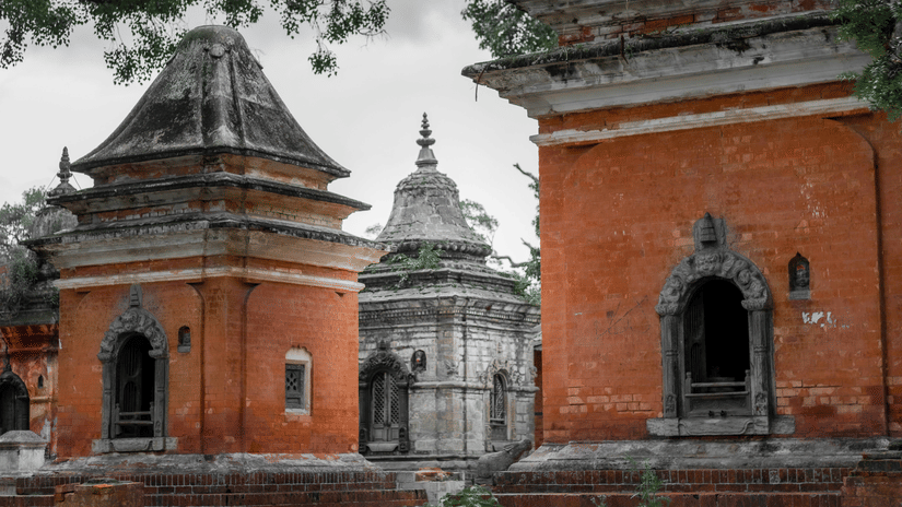 Two small, decorative temples with domed roofs surrounded by trees.